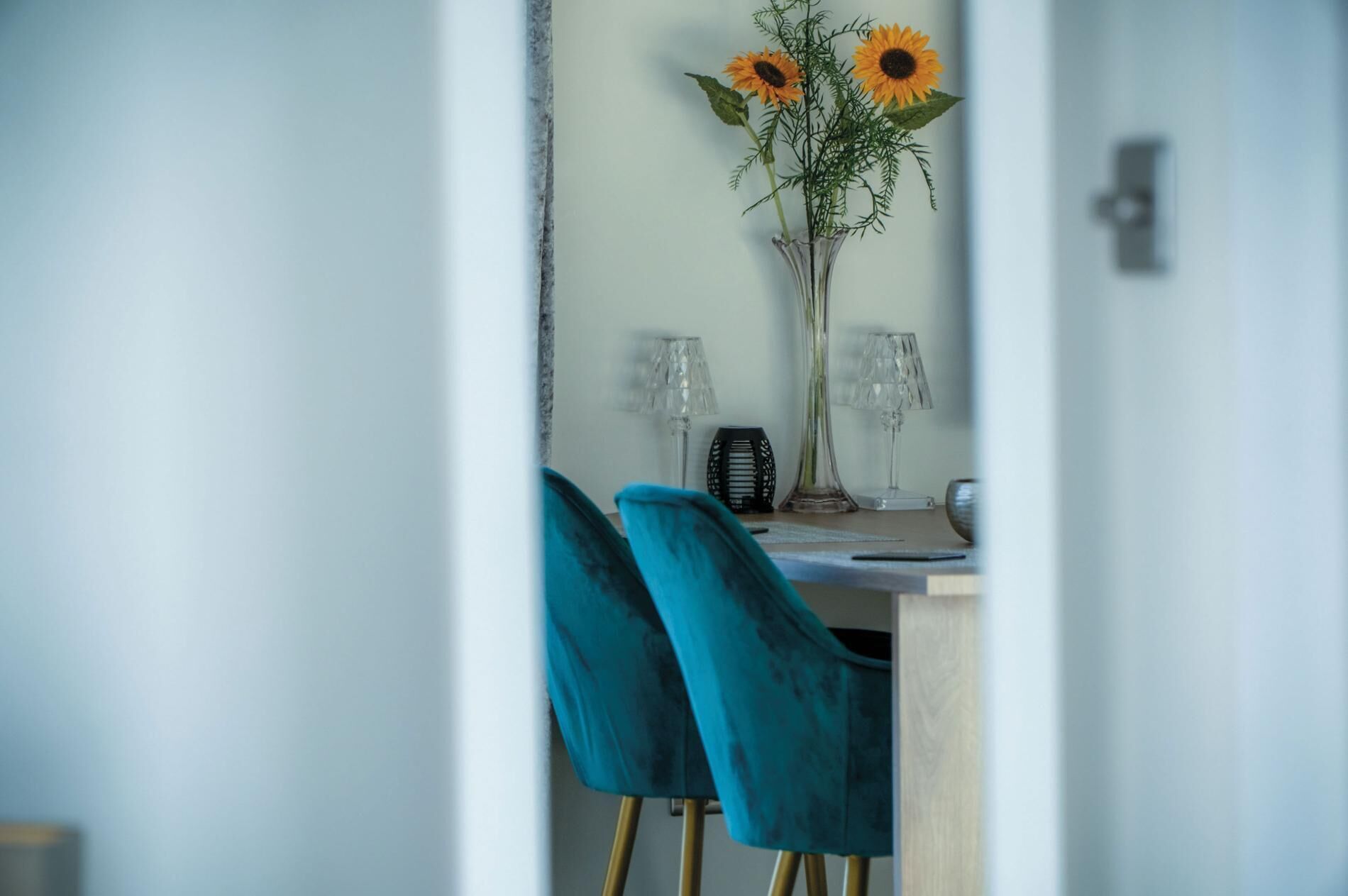 Un comedor con una mesa, dos sillas y un florero con girasoles.