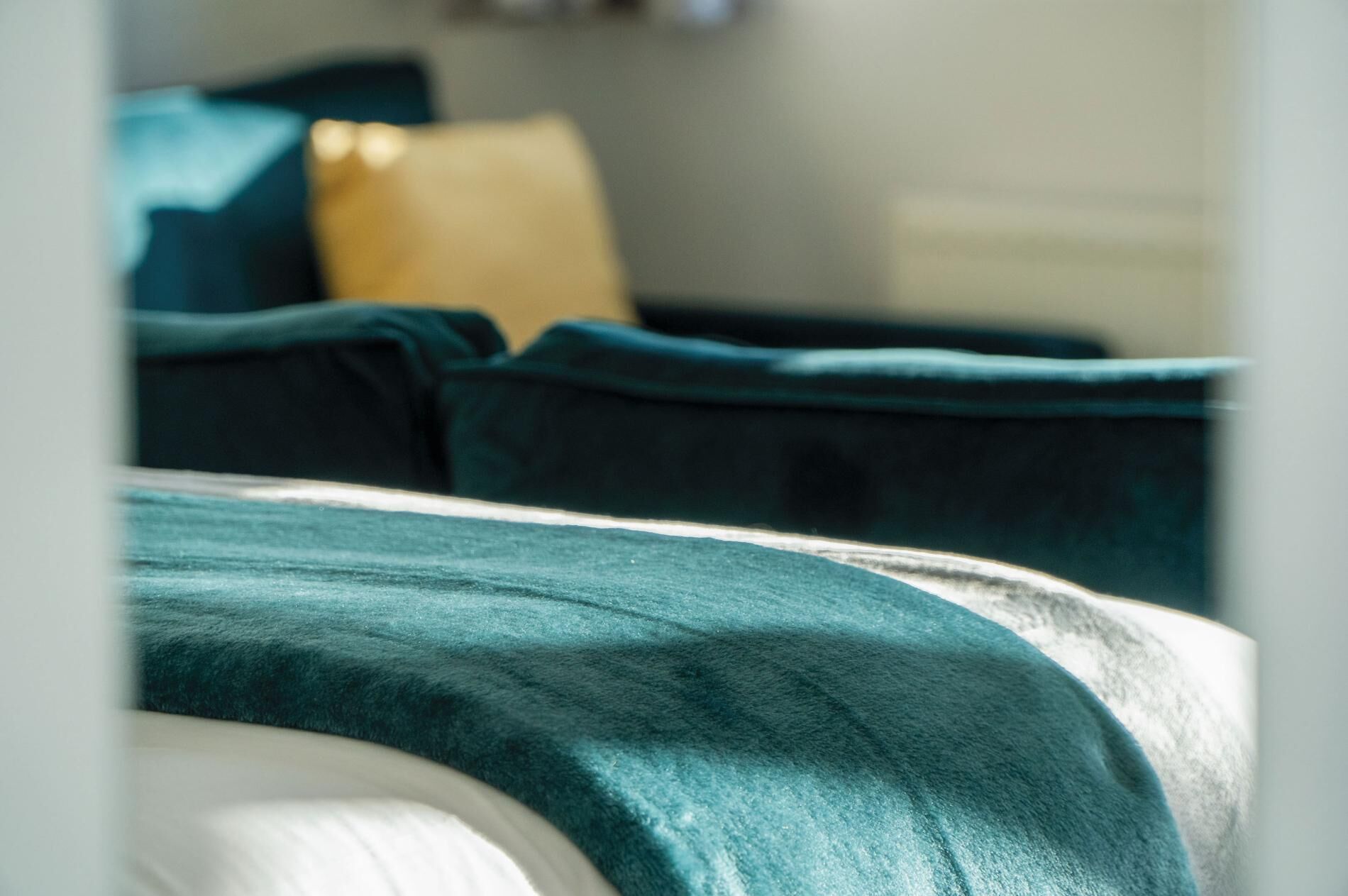 Een bed met smaragdgroene beddengoed en een wit kussen.