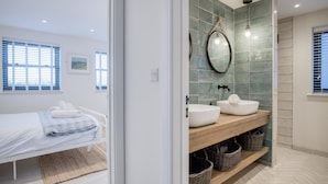 A modern bathroom with a large mirror, two sinks, and a wooden vanity.