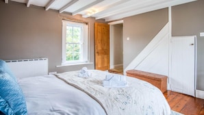 Ein Schlafzimmer mit Bett, Fenster, Holztür und einer Treppe.