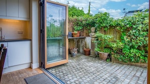 Eine moderne Küche mit einer Schiebetür aus Glas, die auf eine gepflasterte Terrasse führt.