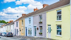 A row of colorful terraced houses with a clear blue sky and fluffy clouds above.