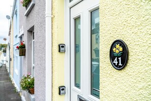 A row of houses with flower boxes on the windowsills and a house number 41 with a flower decoration. - Woodville Road - 2 Bedroom House - Mumbles (Swansea)