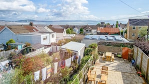 A residential area with houses, a patio with seating, and a view of the sea.
