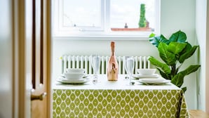 A dining table set with white plates, clear glasses, and a bottle of champagne.