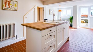 A kitchen with a wooden countertop, white cabinets, and a view to the outside.
