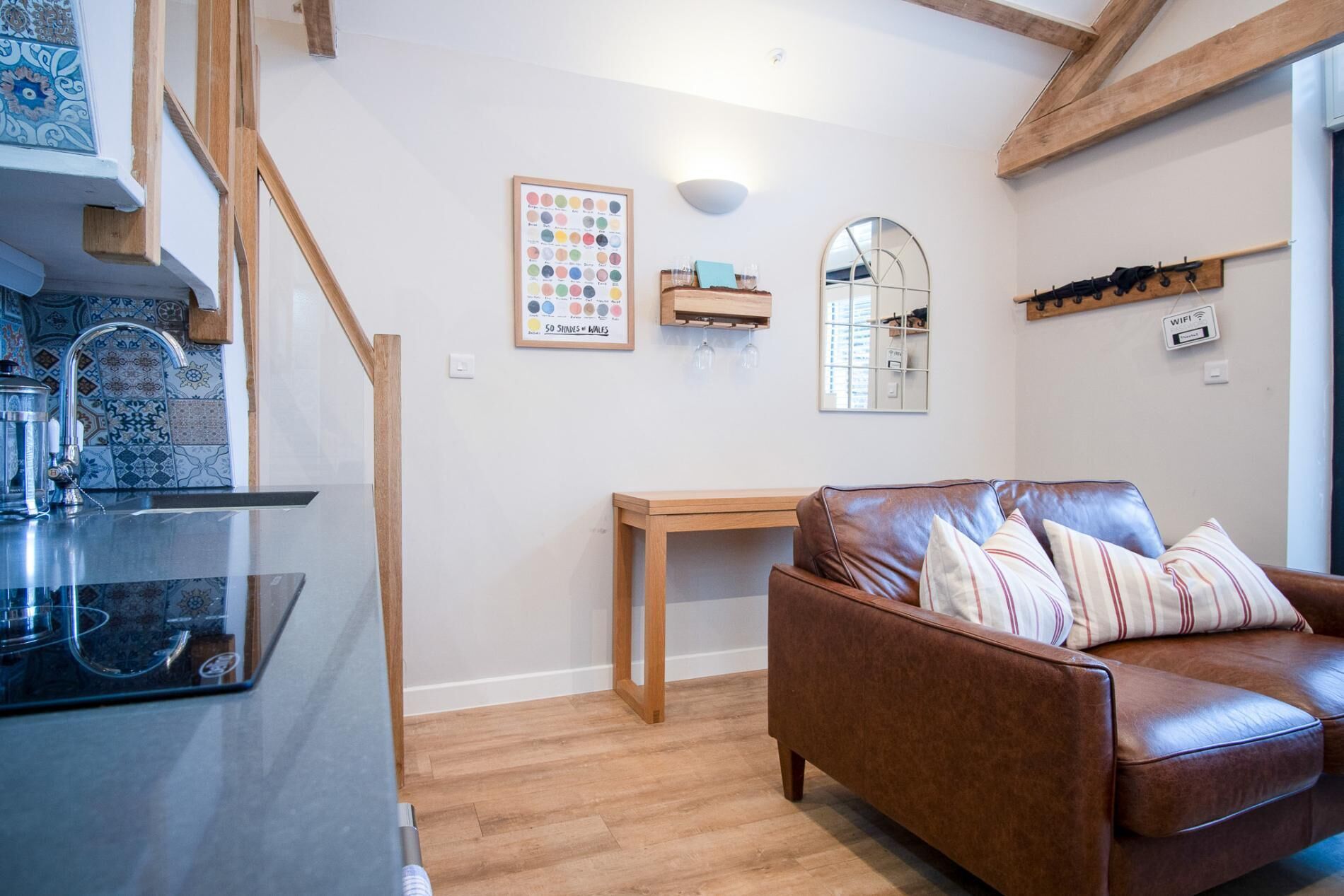 Un salon chaleureux avec un canapé en cuir marron, une table basse en bois et un mur recouvert de carreaux.