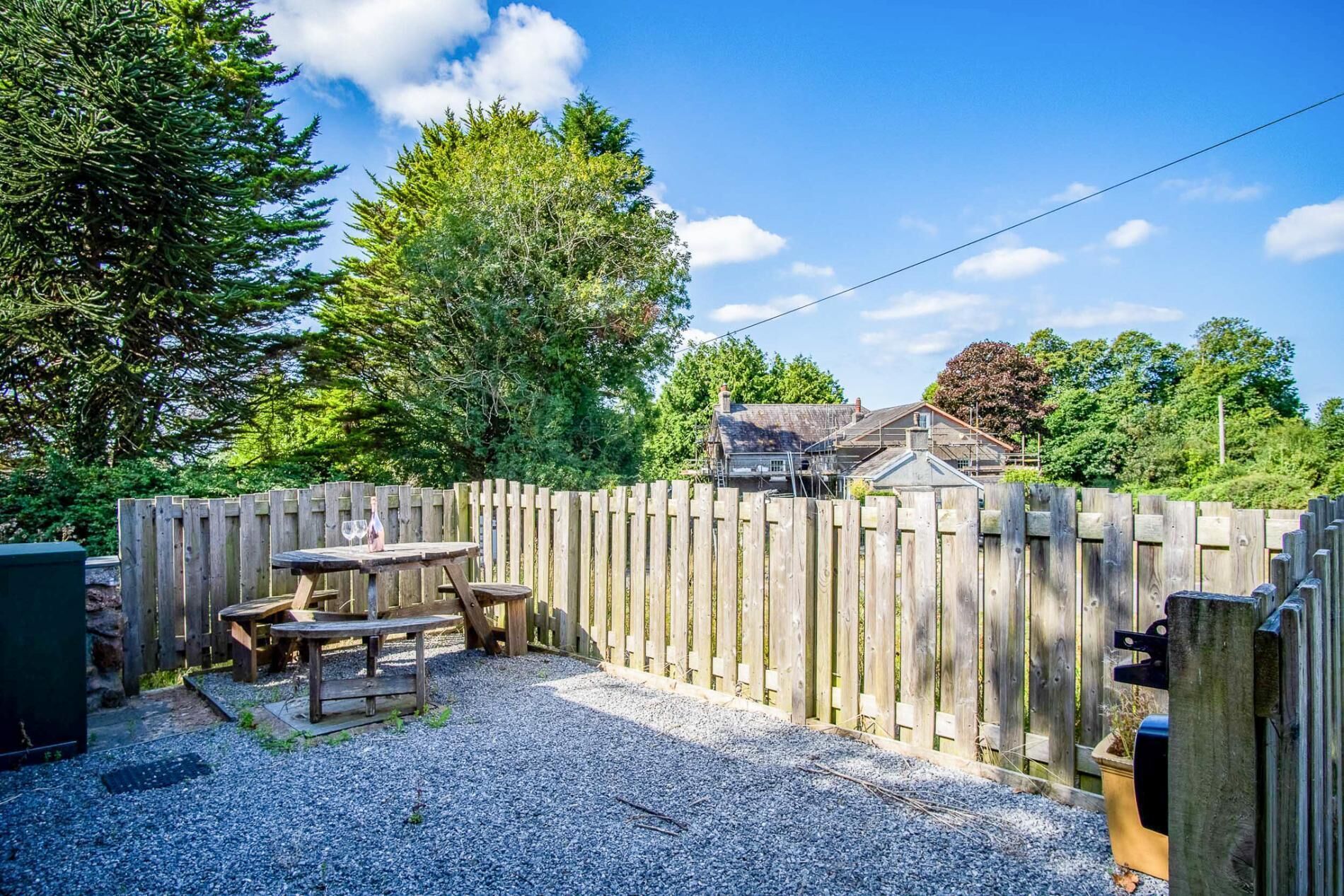 A backyard with a wooden fence, a table, and a bench.