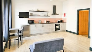 Une cuisine moderne équipée d’un téléviseur à écran plat, d’un four à micro-ondes et d’une cuisinière. Un coin repas avec une table et des chaises est également à disposition.