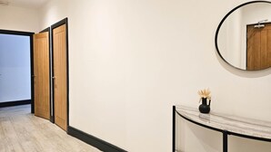 Un couloir avec des portes en bois, une console en marbre et un grand miroir rond accroché au mur.