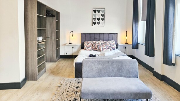 Une chambre moderne avec un lit, des tables de chevet, une armoire et une grande fenêtre avec des rideaux.