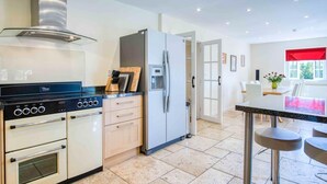 A modern kitchen with a stove, oven, refrigerator, and a dining area with a table and chairs.
