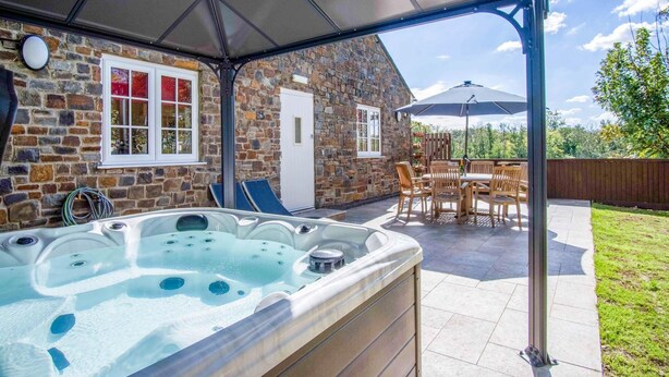 A stone building with a hot tub, outdoor seating, and a covered patio area.