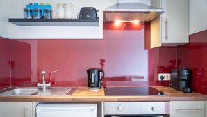 Eine moderne Küche mit Spüle aus Edelstahl, einer Kaffeemaschine und einem Geschirrspüler.