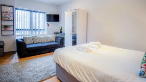 Ein modernes Hotelzimmer mit einem großen Bett, einer Couch, einem Fernseher und einem Kleiderschrank.