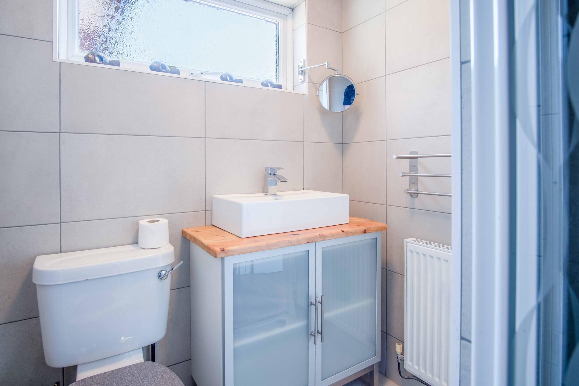 Un baño pequeño con inodoro, lavamanos con espejo y zona de ducha.