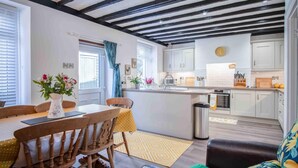 Une cuisine moderne avec des meubles blancs, un îlot central et un coin repas comprenant des chaises et une table en bois.