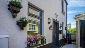 Un bâtiment blanc avec une porte noire, une fenêtre agrémentée d’une jardinière et une enseigne indiquant « Rose Cottage ».