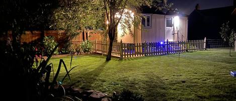 A house with a fenced backyard, a small pond, and a tree.