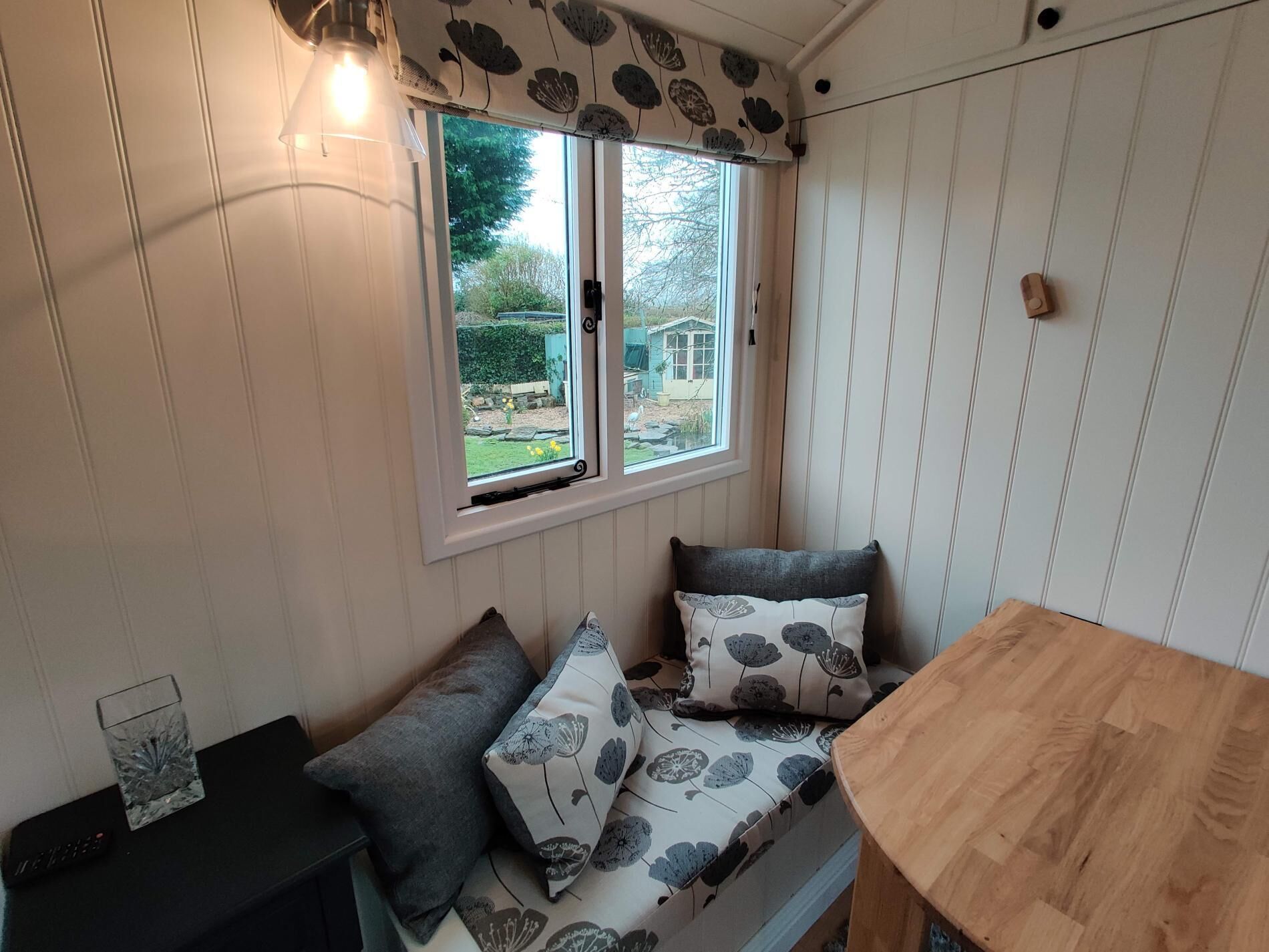 A cozy room with a bench, a small table, and a window with a view of a garden.