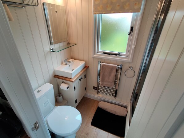 A compact bathroom with a toilet, sink, and window. - Duck House - 1 Bed Shepherds Hut - Gower (Swansea)