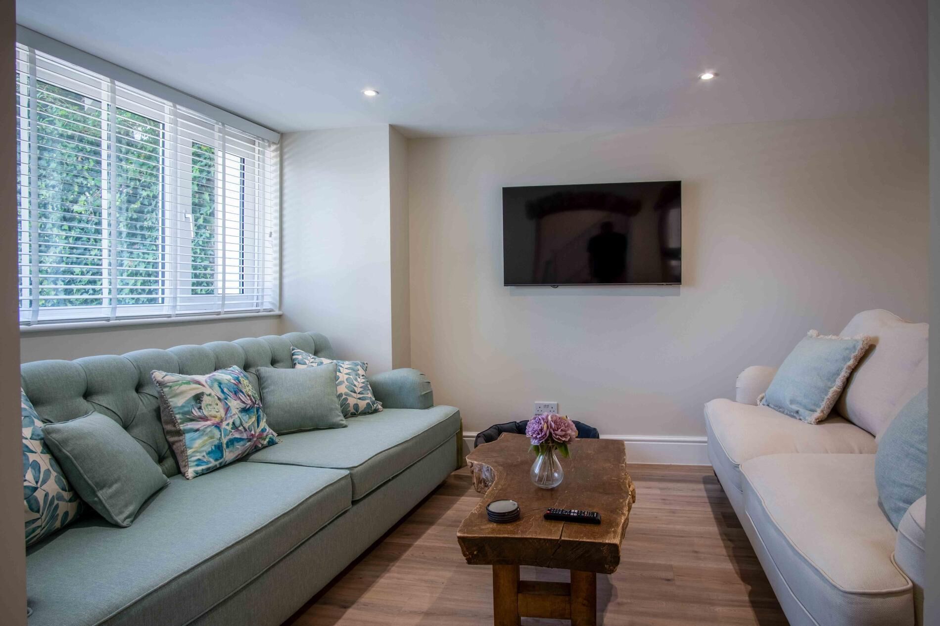 A living room with a sofa, a coffee table, and a TV mounted on the wall.