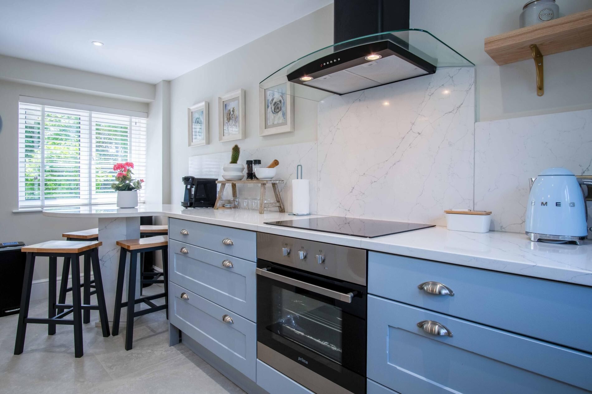 A modern kitchen with a marble backsplash, stainless steel appliances, and a glass hood vent.