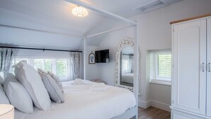 Ein Schlafzimmer mit einem großen Bett, einem Kleiderschrank, einem Spiegel und einem Fernseher.