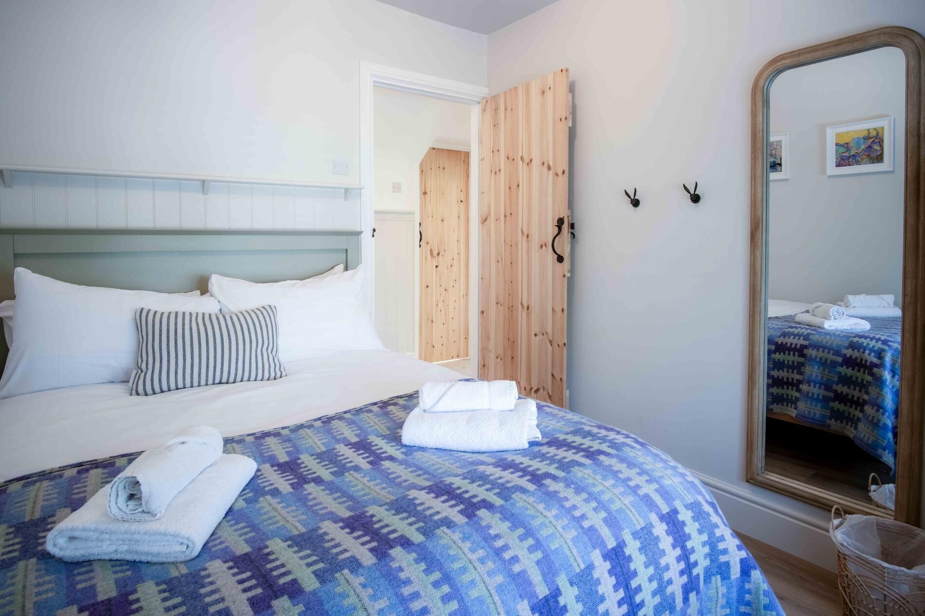 A hotel room with a bed, a large mirror, and a wooden door.