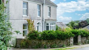 A two-story house with a stone wall in front, a small garden, and a clear blue sky. - Fern Bank - 5 Bedroom House - Horton (Swansea)