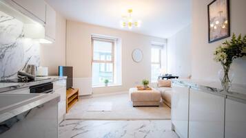 A modern kitchen with marble countertops, a built-in oven, and a dining area with a sofa and a small table.