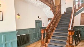 Una scala con balaustre in legno e corrimano che conduce a una porta con pannello verde.