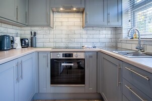 Una cocina moderna con gabinetes grises, horno empotrado y un lavamanos de acero inoxidable.