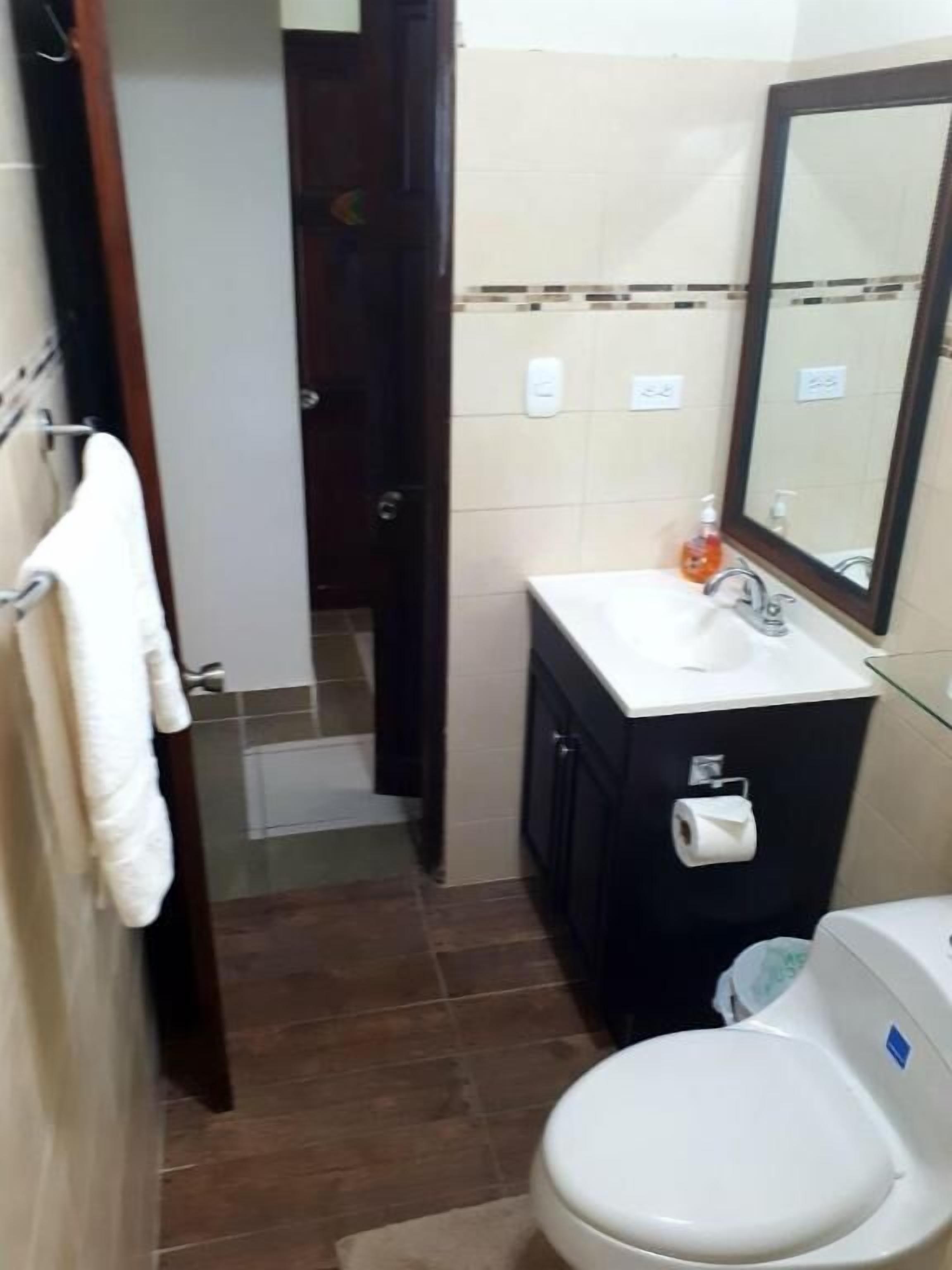 A small bathroom with a white toilet, a sink with a mirror above it, and a towel rack.