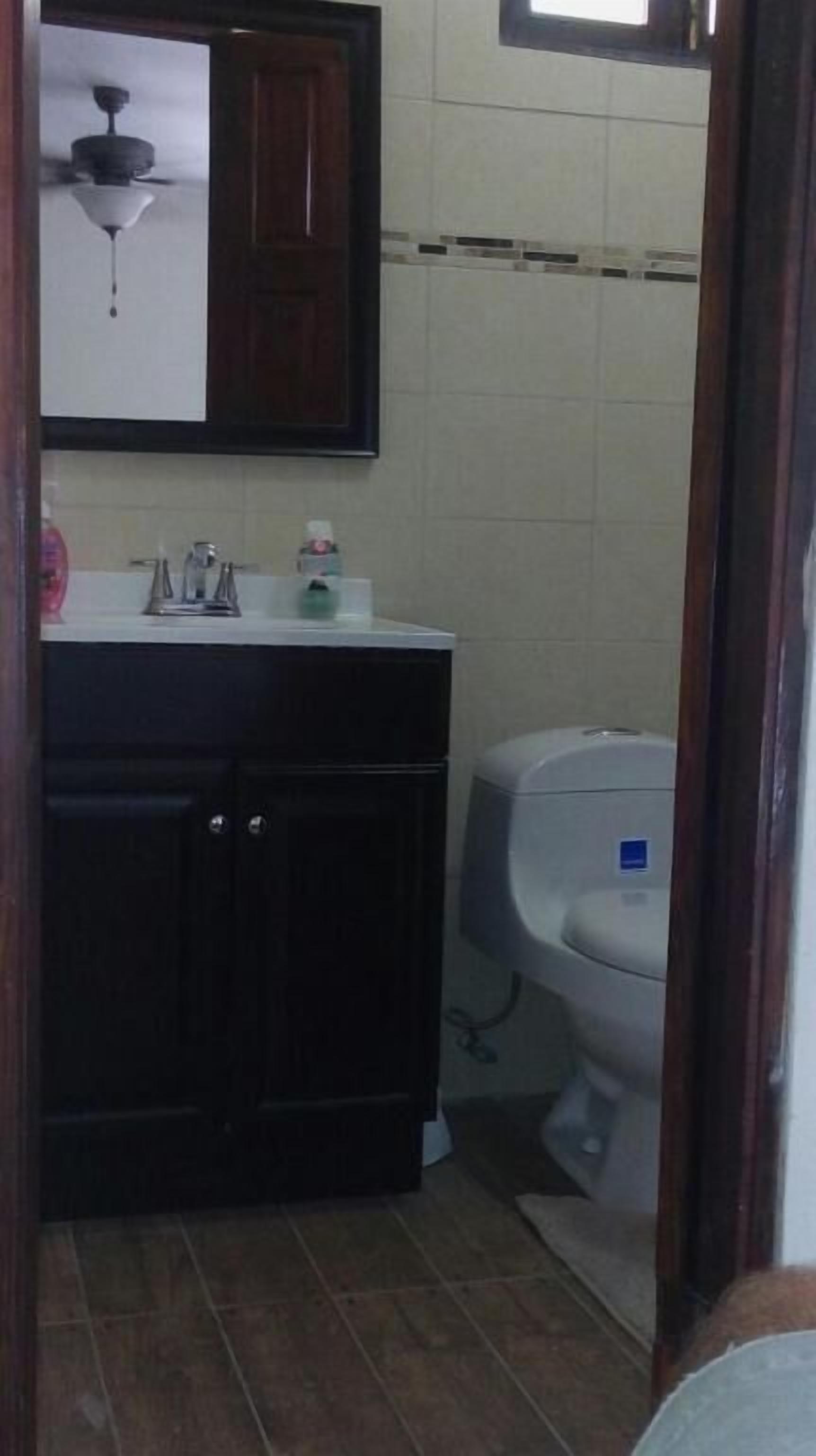 A bathroom with a dark wooden cabinet, a white sink, and a toilet.