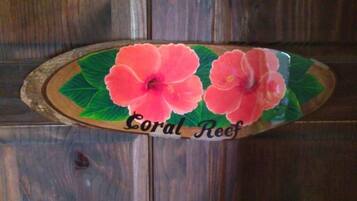 Una placa de madera con dos flores rosadas y el texto 'Coral Reef'.