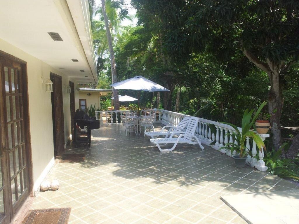 Un espace extérieur abrité, doté d’un sol carrelé, de chaises longues blanches et de parasols.