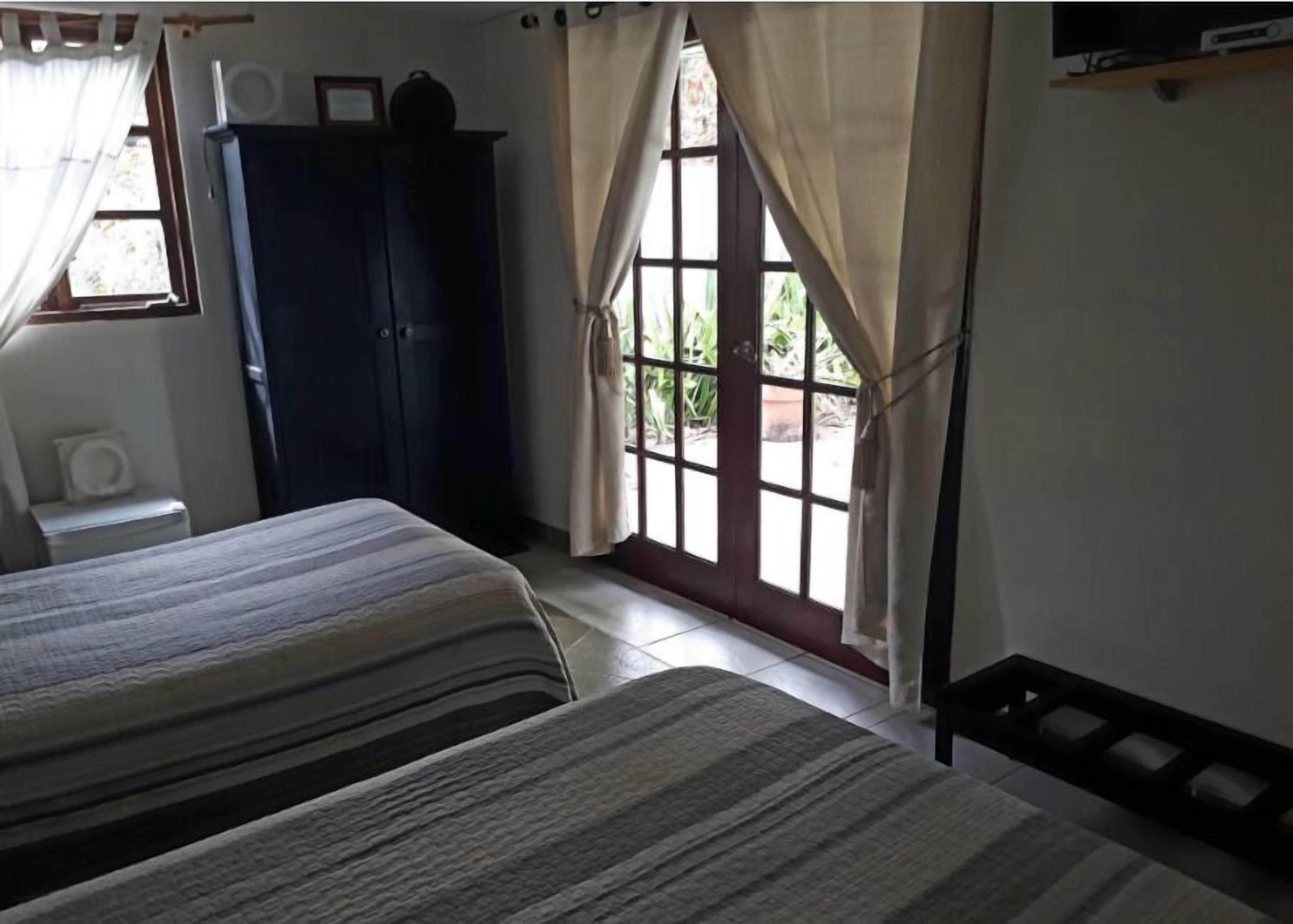 Un dormitorio con dos camas, un armario y una ventana con cortinas.