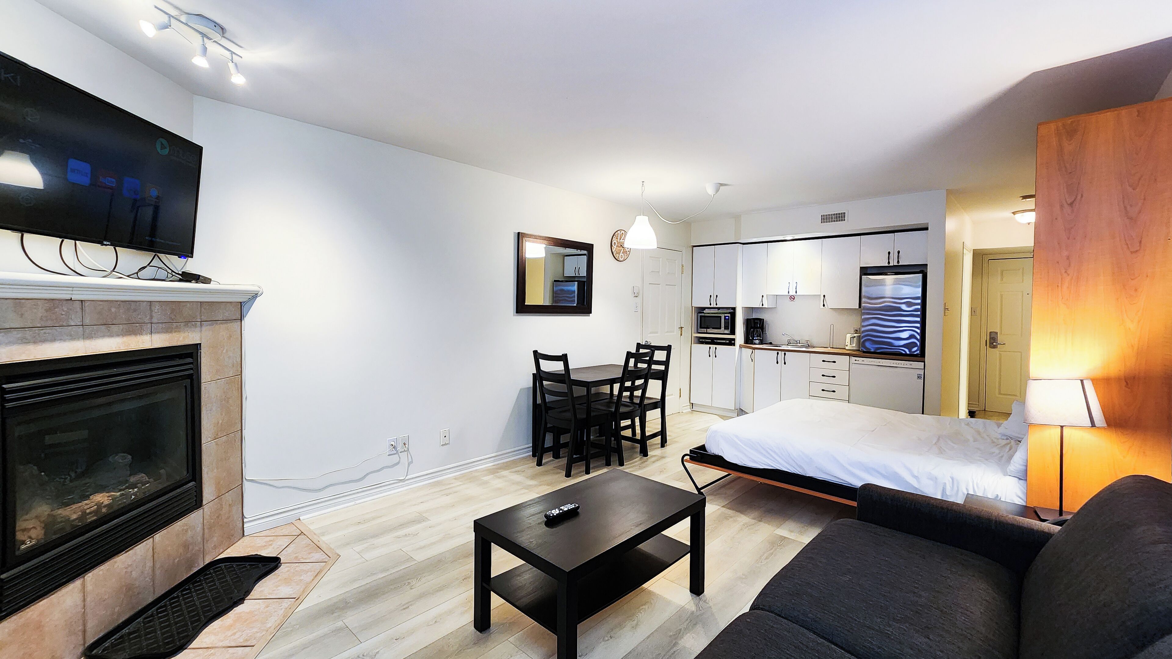 Et moderne hotelværelse med pejs, spiseplads, seng og tekøkken.