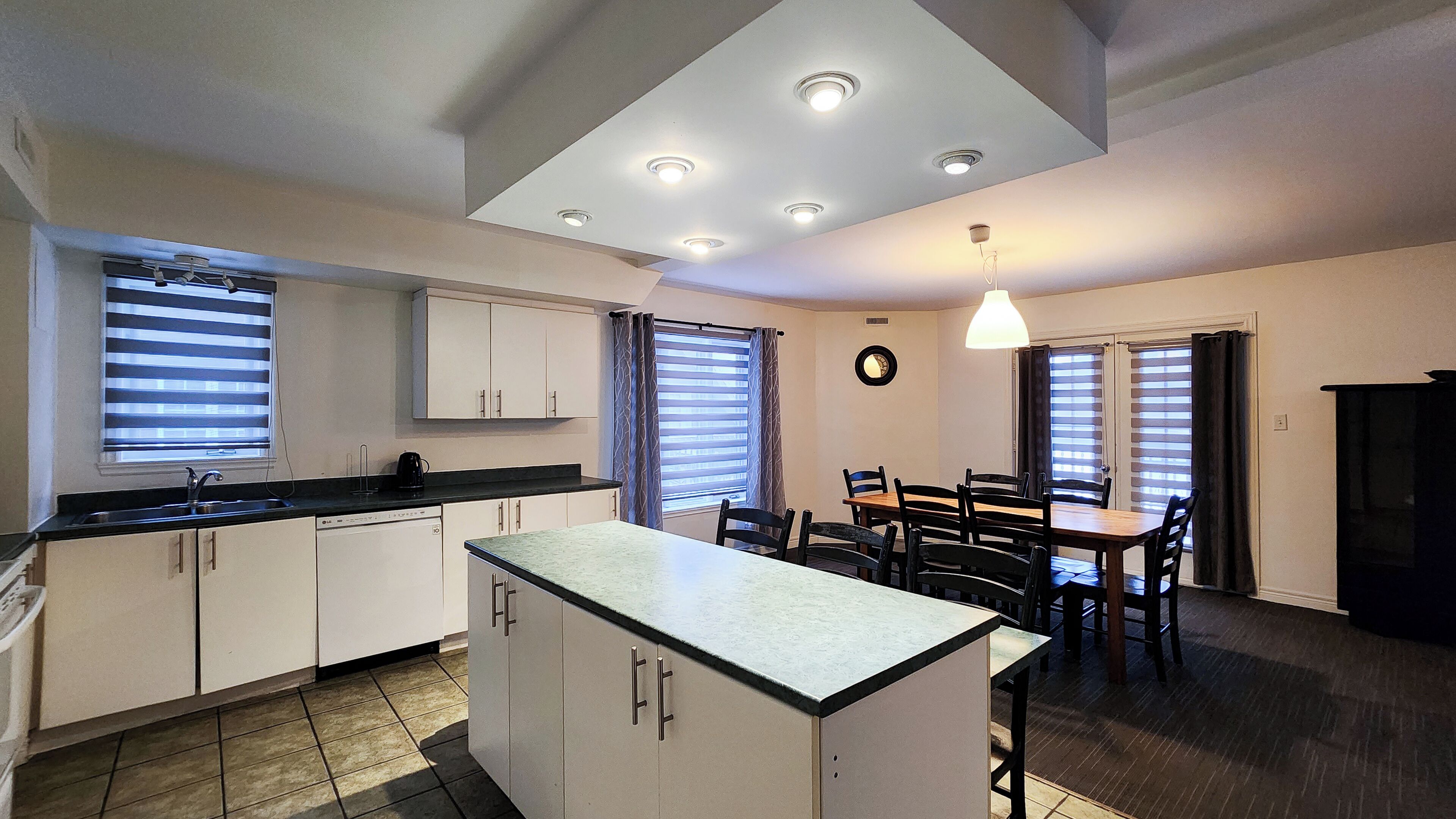 A compact kitchen with a central island, a dining area with a table and chairs, and a ceiling with recessed lighting.