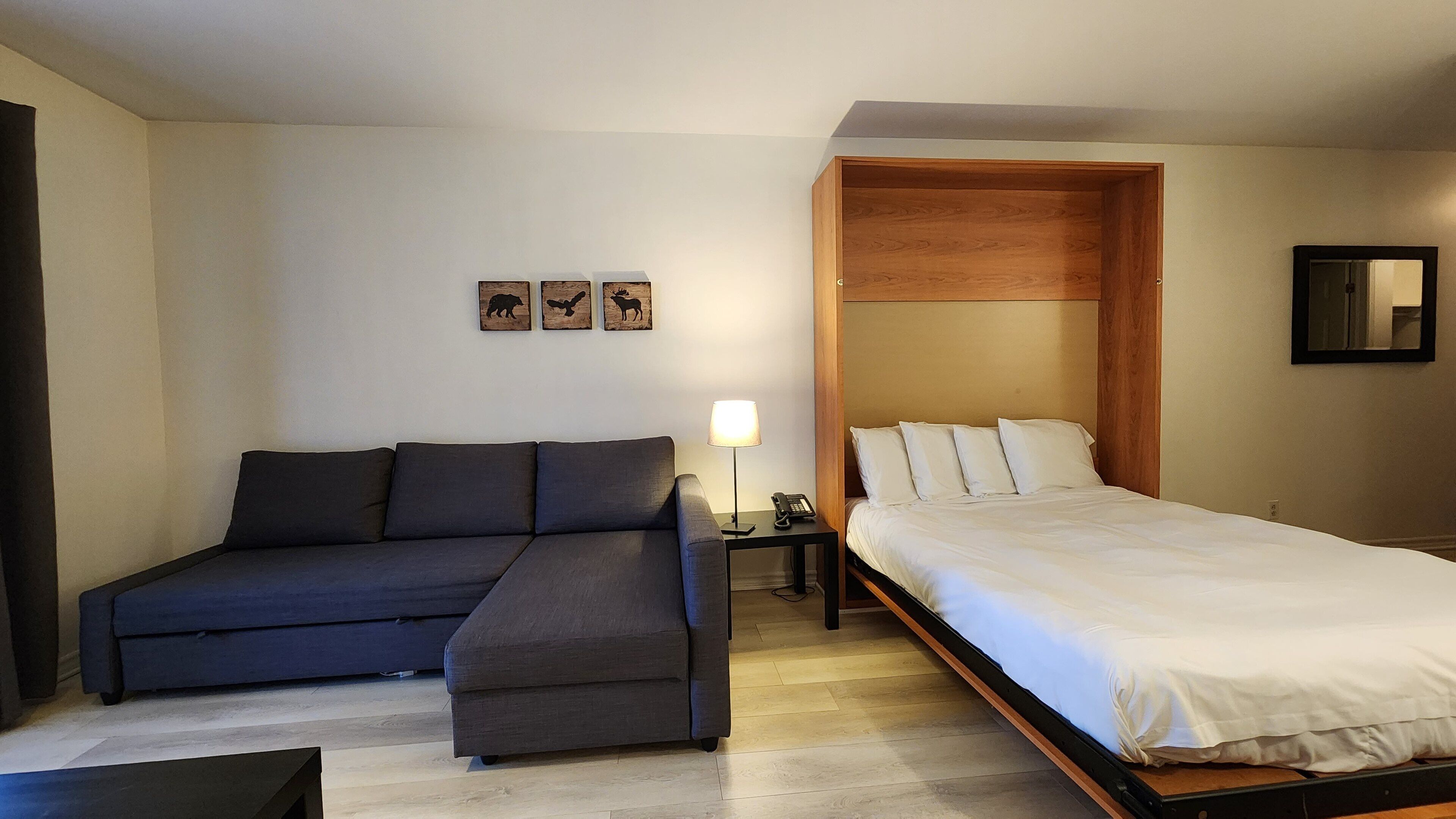 Een slaapkamer met een bed, een bank, een nachtkastje met lamp en een kleine tafel met telefoon.