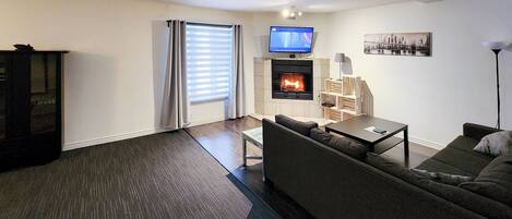 A modern living room with a fireplace, a television, and a sofa.