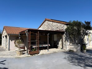 Un edificio de piedra con techo de tejas, un porche de madera y una rueda grande.