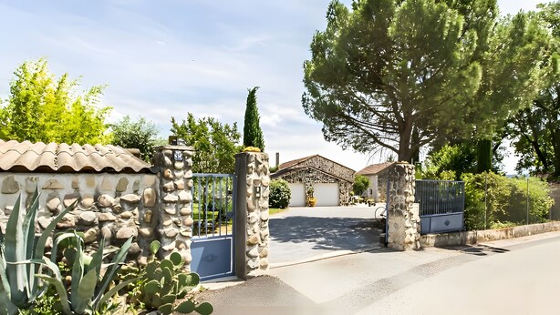 A gated entrance with a stone wall, a cactus plant, and a large tree. - Gite Stéphanie l'Ephedra – Charming 3-Star Home with Pool in Sampzon (Sampzon)