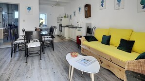A compact living space with a dining area, kitchenette, and a yellow sofa with patterned cushions. - Gite Stéphanie l'Ephedra – Charming 3-Star Home with Pool in Sampzon (Sampzon)
