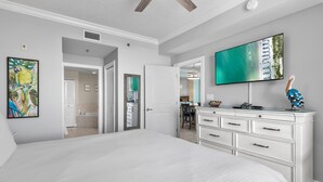 A bedroom with a large bed, a white dresser, a flat-screen TV, and artwork on the walls. - Azure #112 (Fort Walton Beach)
