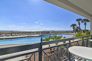 A pool area with lounge chairs and a view of the ocean.