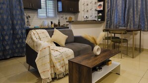 A modern living room with a grey sofa, a wooden coffee table, and a dining area with a small table and chairs.