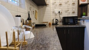 A kitchen with a granite countertop, a microwave, a kettle, and a knife block.