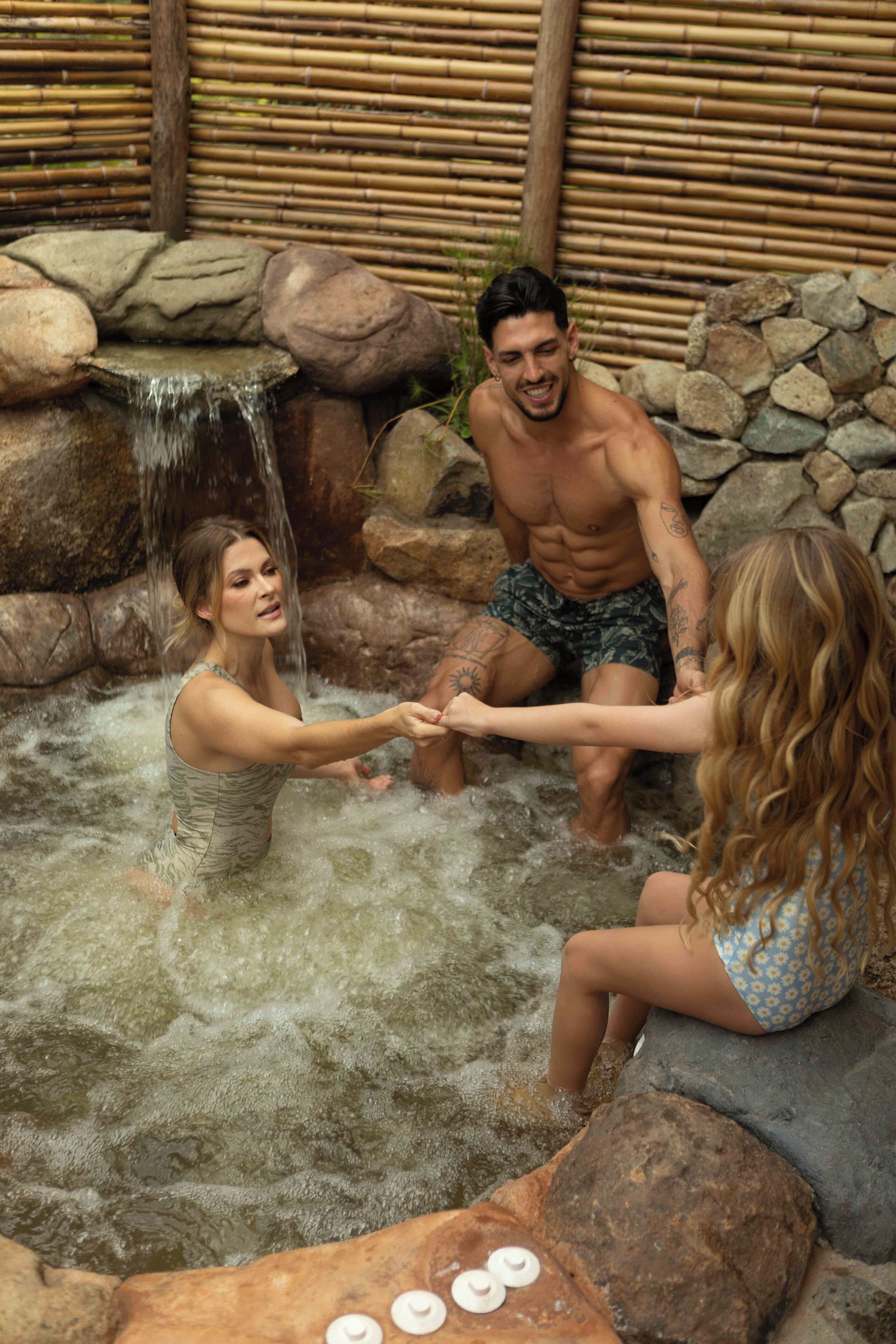 A hot spring area with a waterfall, rocks, and people.